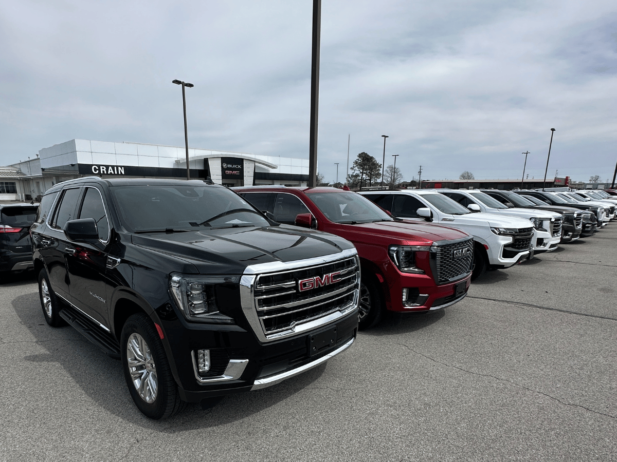 Row of new GMC SUVs parked outside Crain Buick GMC in Springdale, showcasing a premium inventory for trade-in customers.